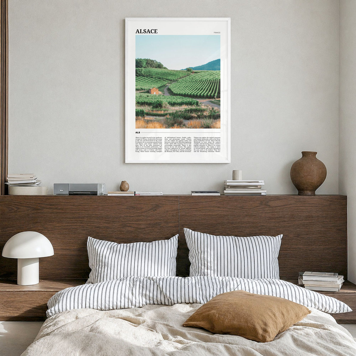 Alsace Travel Poster in a white wood frame, hanging in a bedroom