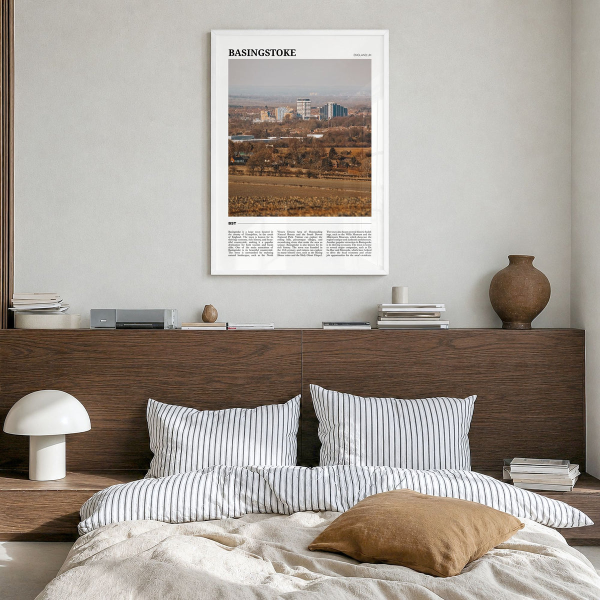 Basingstoke Travel Poster in a white wood frame, hanging in a bedroom