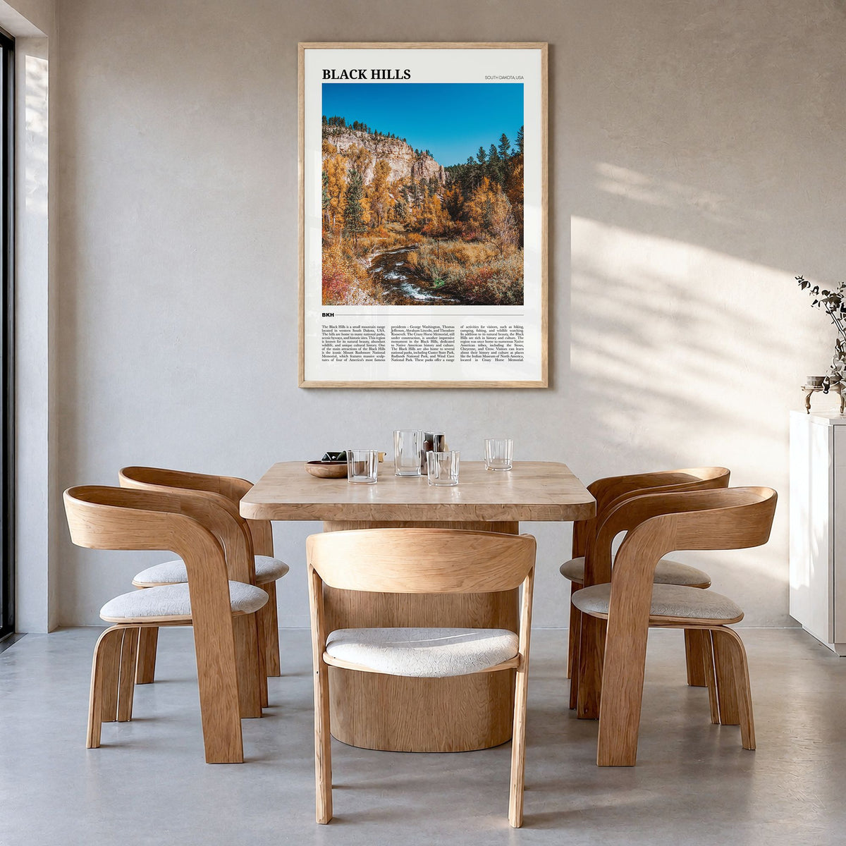 Black Hills Travel Poster in a natural wood frame, hanging in a dining room