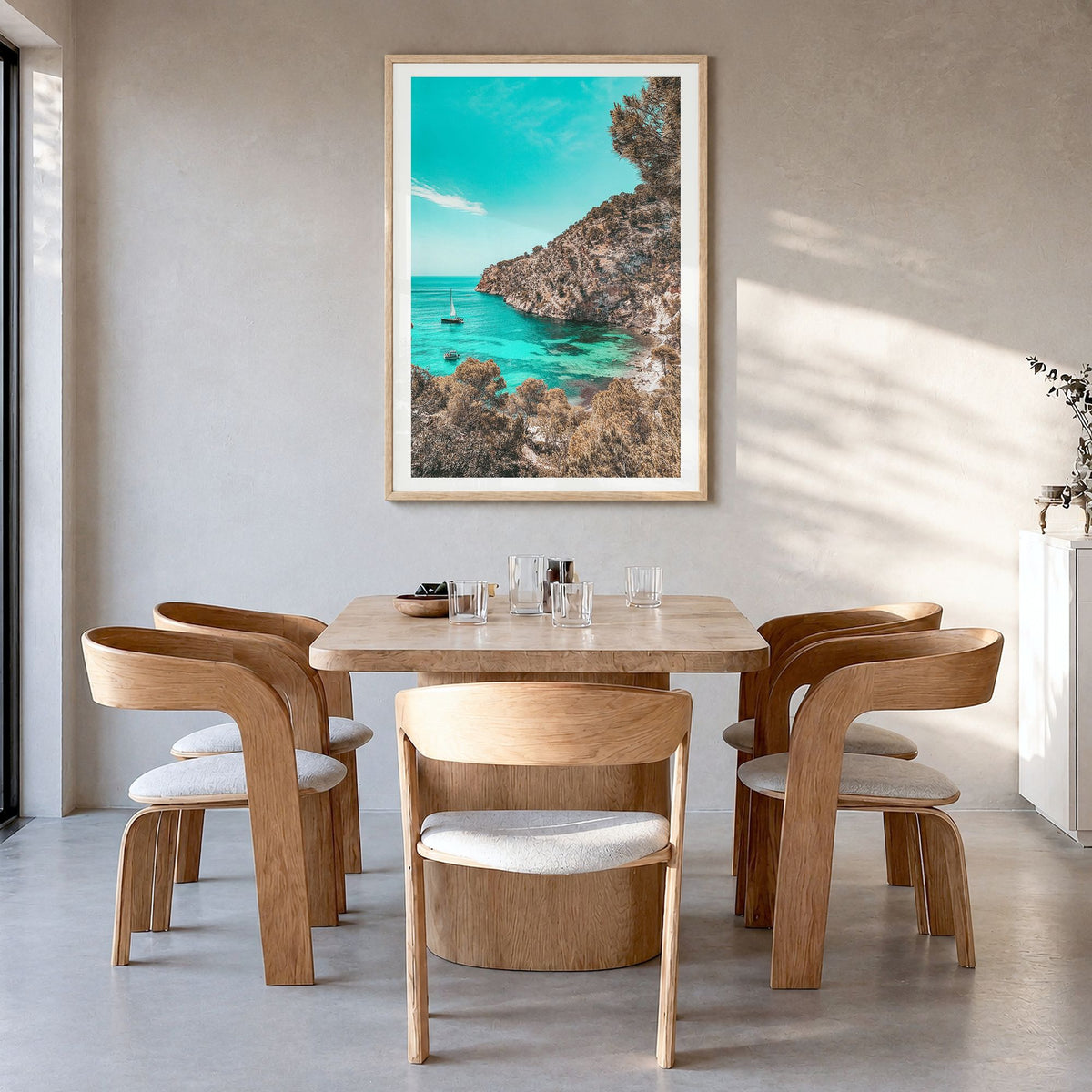 Cala Blanca Photo Poster in a natural wood frame, hanging in a dining room, white border