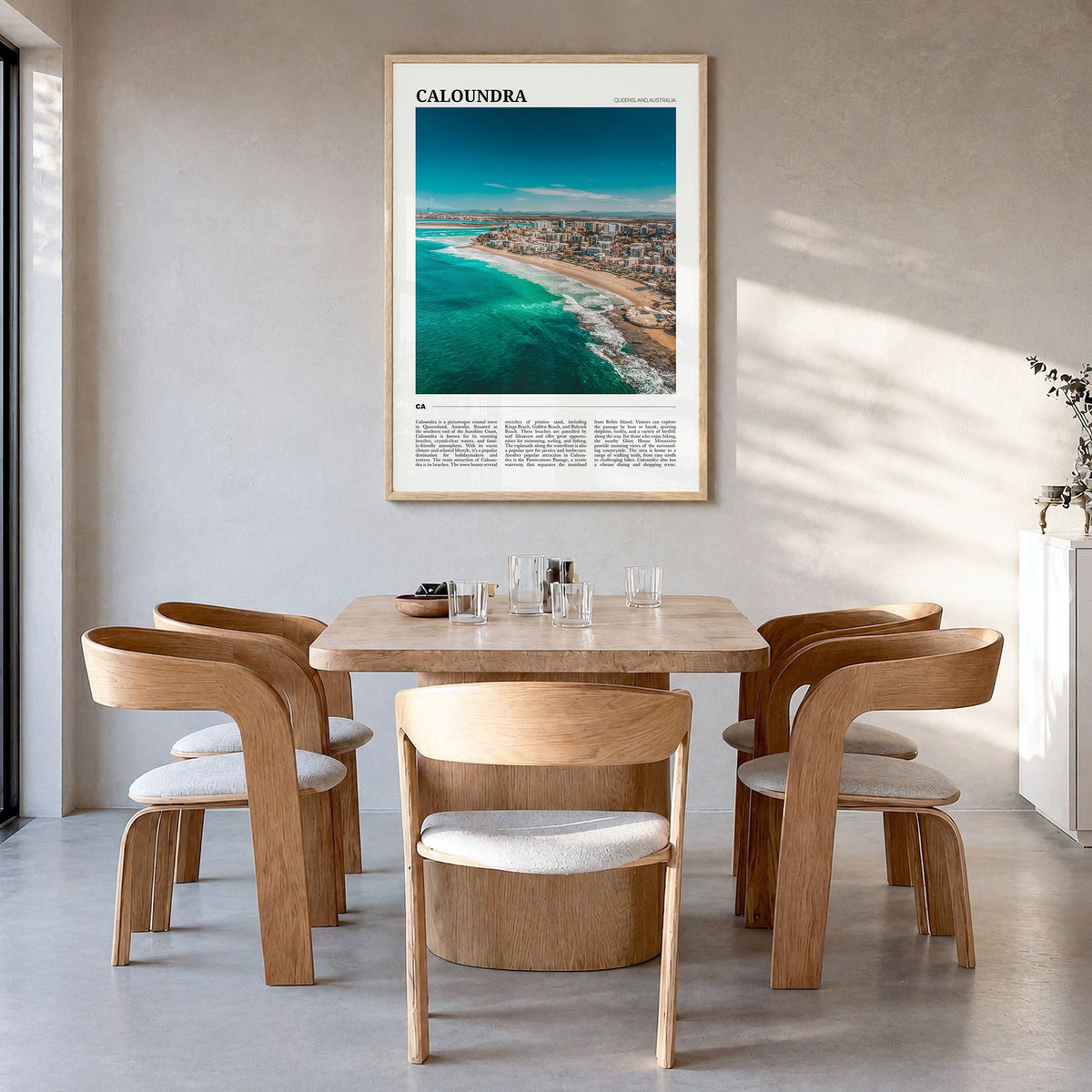 Caloundra Travel Poster in a natural wood frame, hanging in a dining room