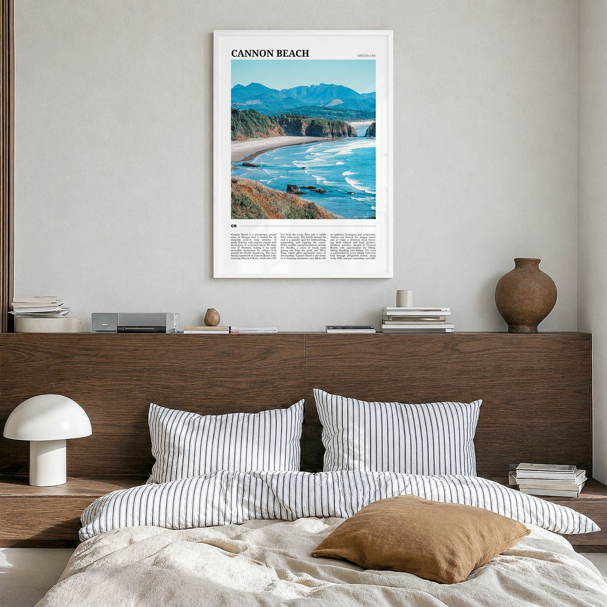 Cannon Beach Travel Poster in a white wood frame, hanging in a bedroom