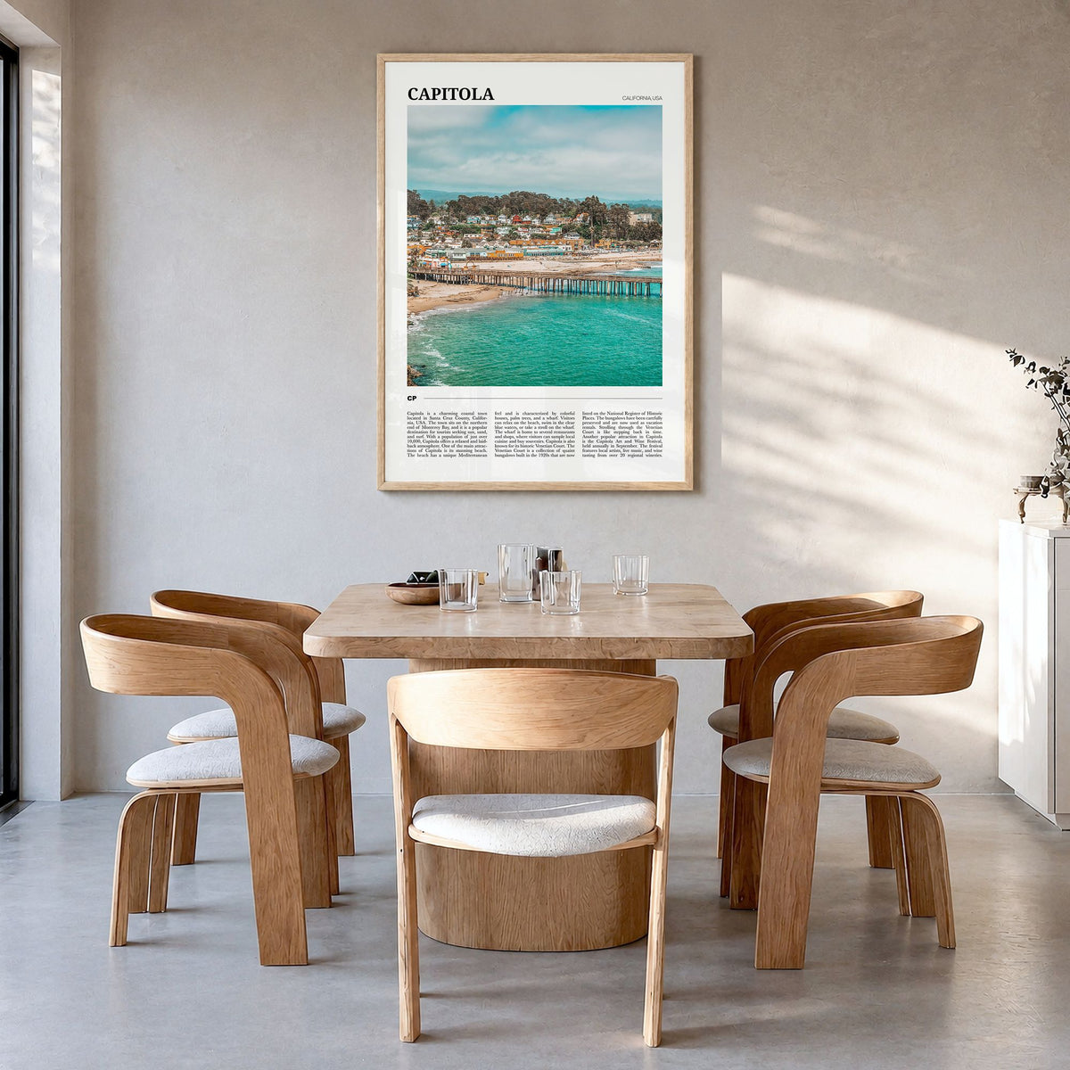 Capitola Travel Poster in a natural wood frame, hanging in a dining room