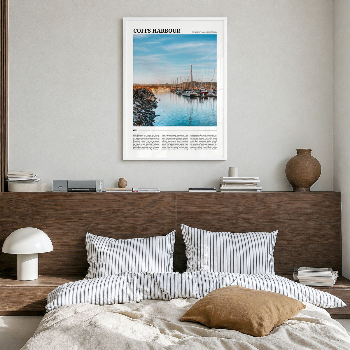Coffs Harbour Travel Poster in a white wood frame, hanging in a bedroom