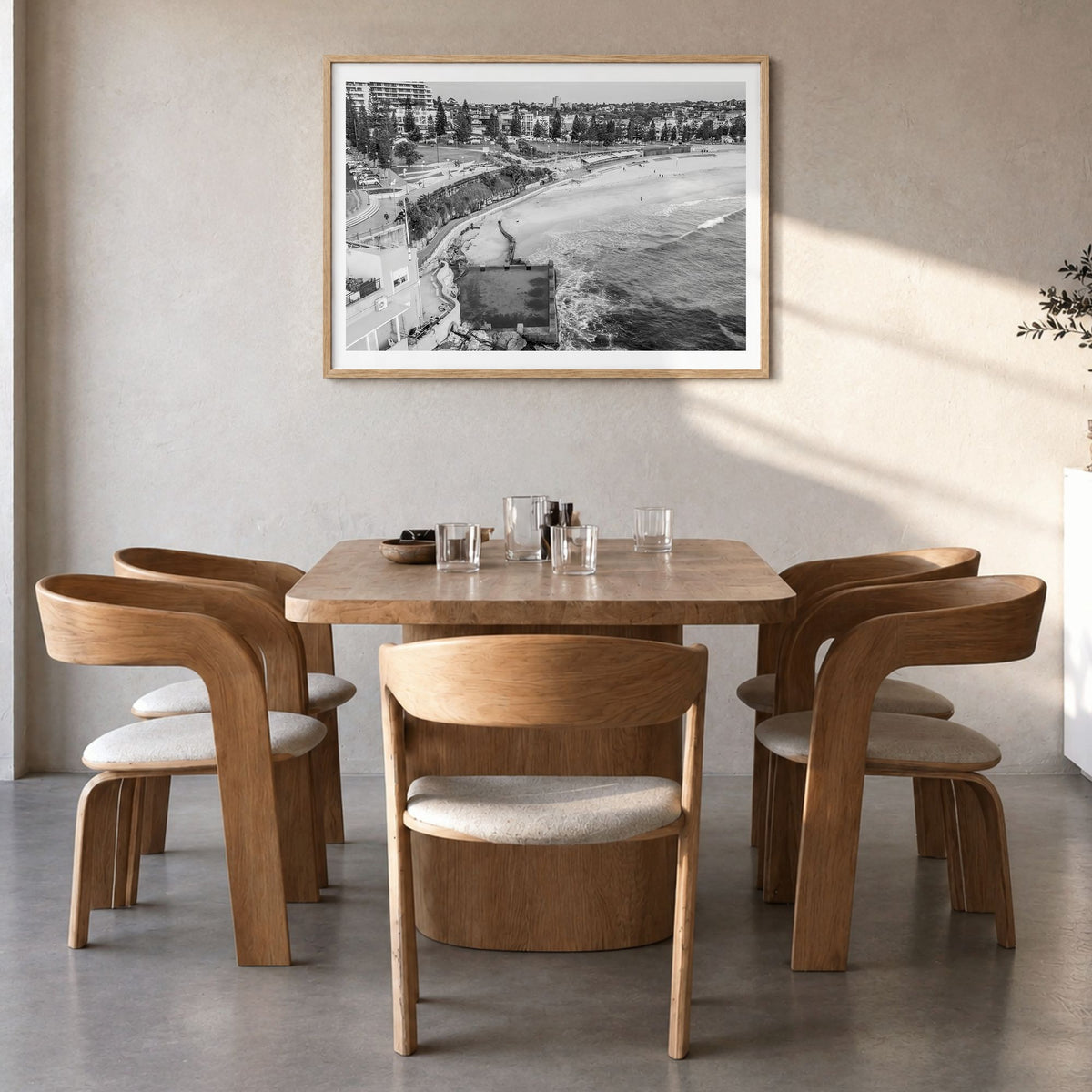 Coogee Beach Photo Poster in a natural wood frame, hanging in a dining room, white border