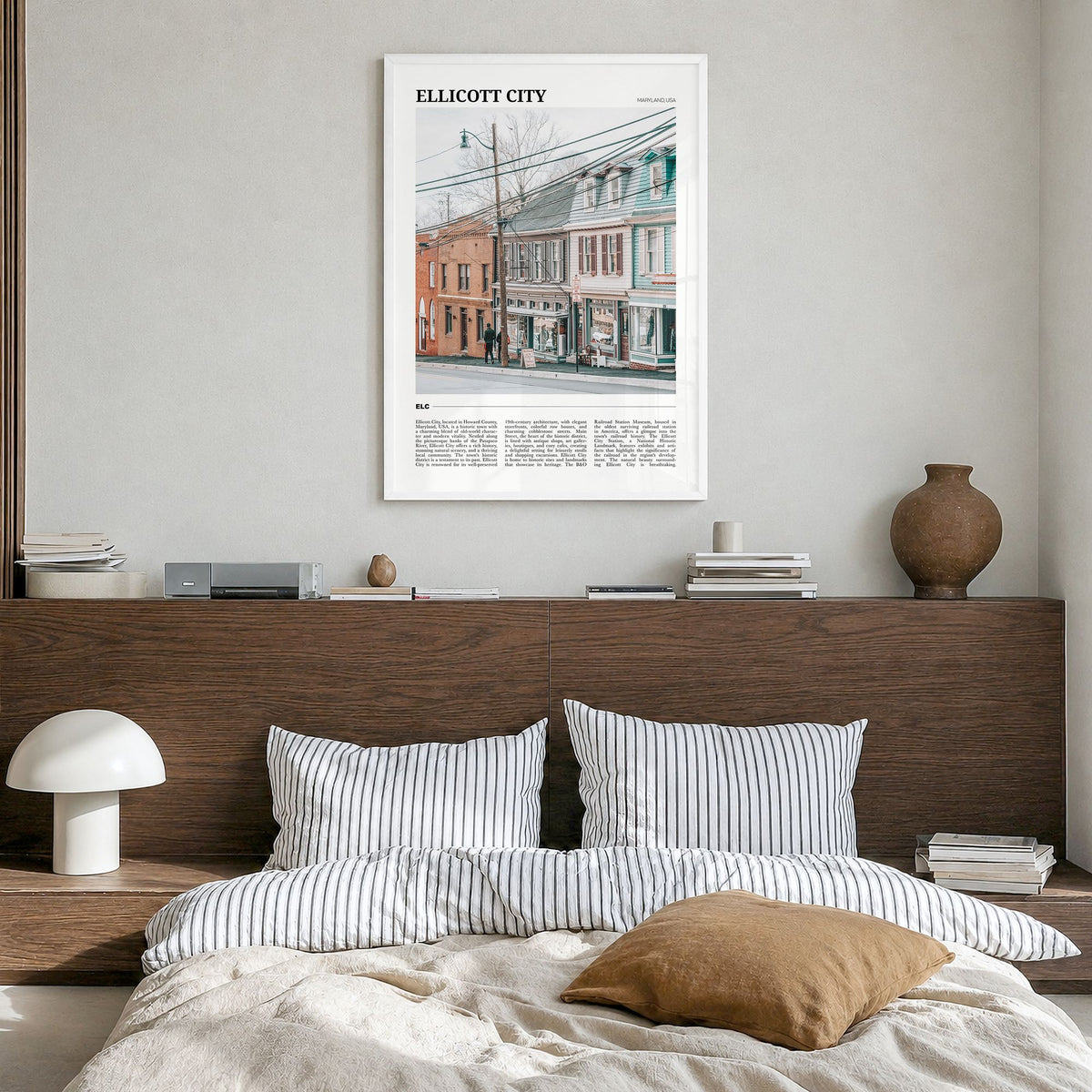 Ellicott City Travel Poster in a white wood frame, hanging in a bedroom