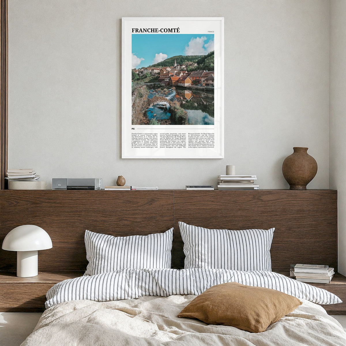 Franche-Comté Travel Poster in a white wood frame, hanging in a bedroom