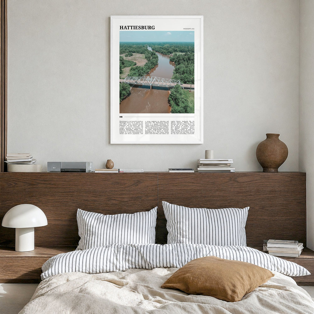 Hattiesburg Travel Poster in a white wood frame, hanging in a bedroom