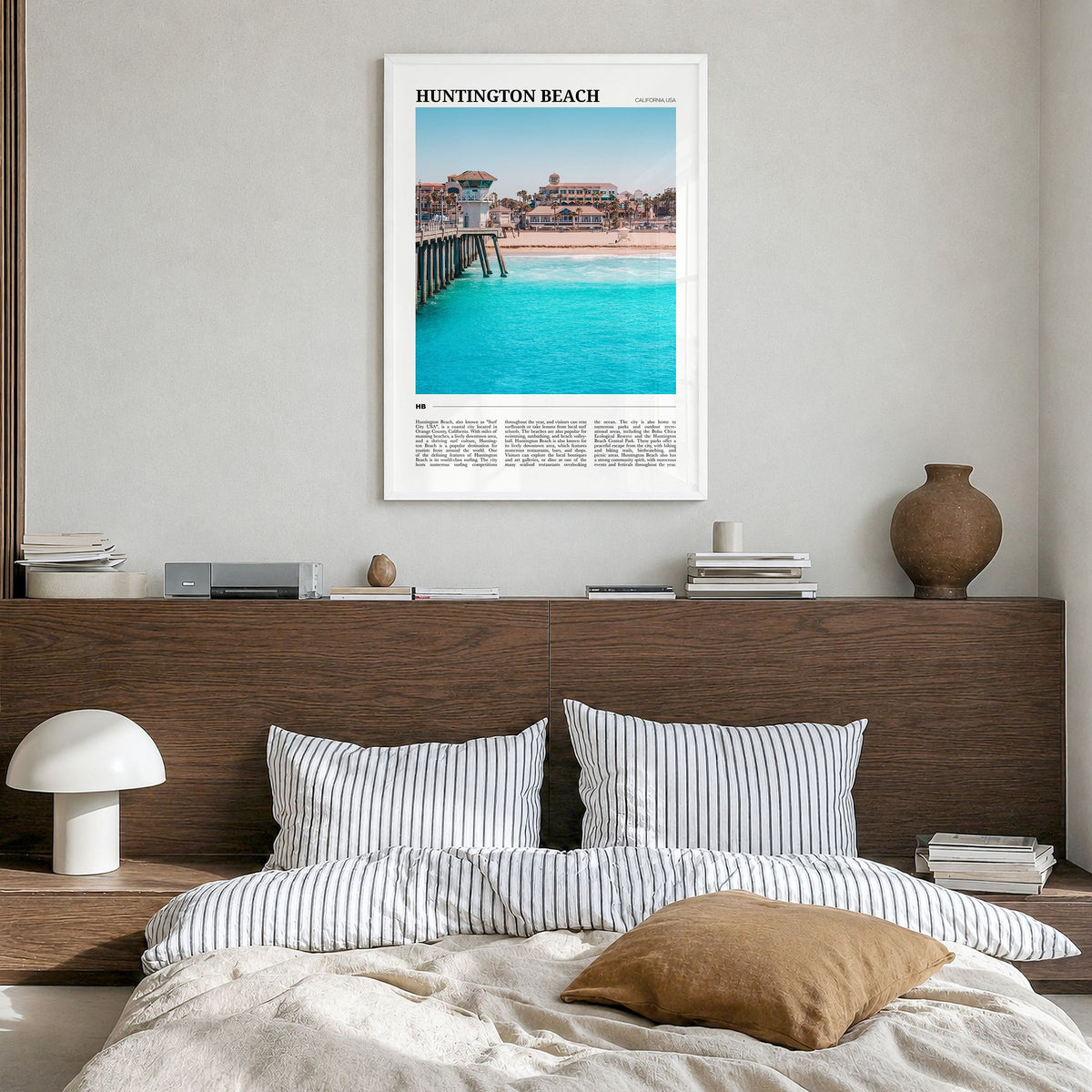 Huntington Beach Travel Poster in a white wood frame, hanging in a bedroom