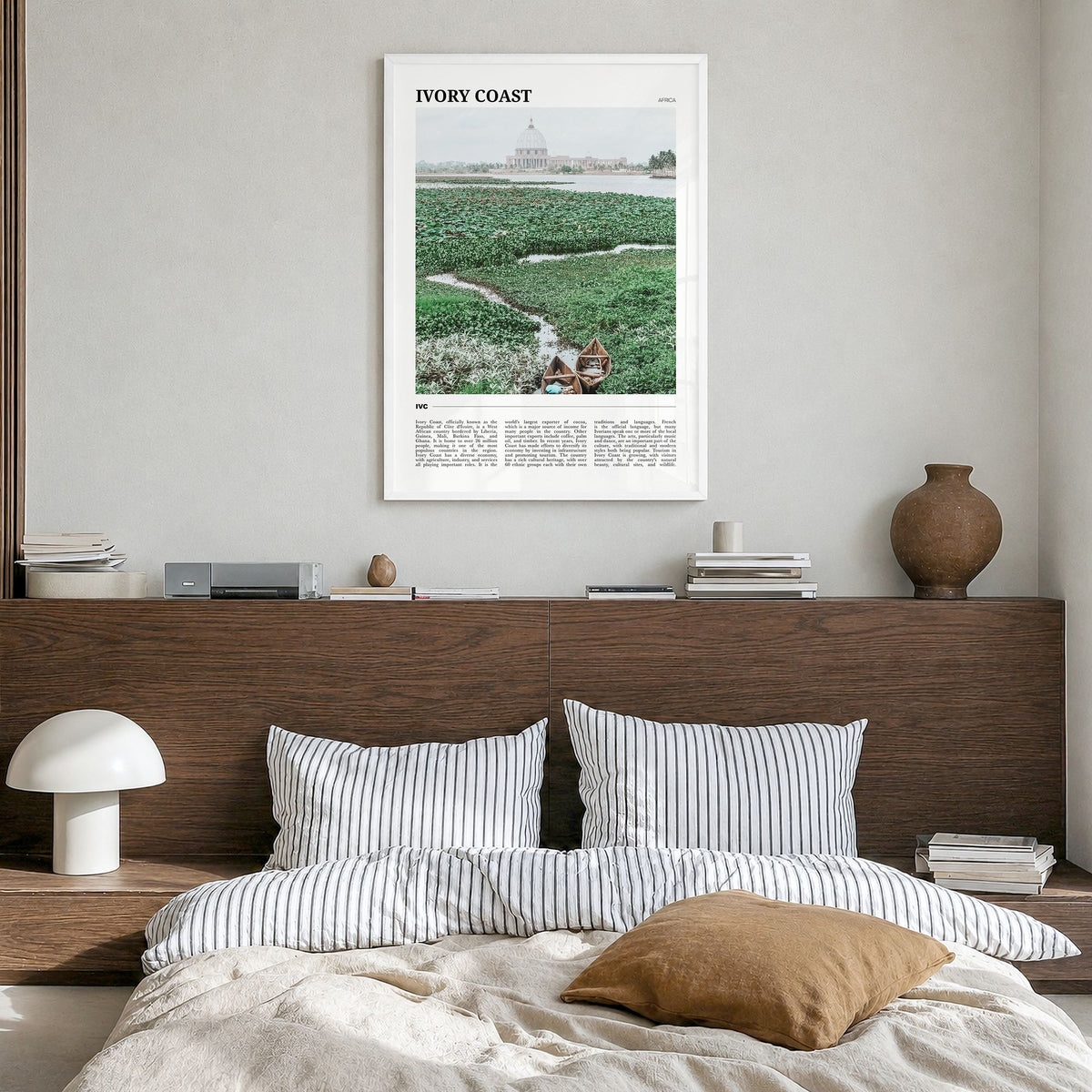 Ivory Coast Travel Poster in a white wood frame, hanging in a bedroom