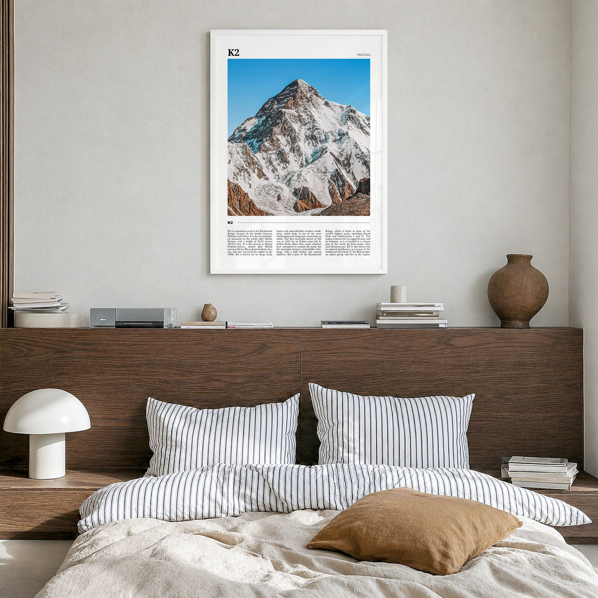 K2 Travel Poster in a white wood frame, hanging in a bedroom