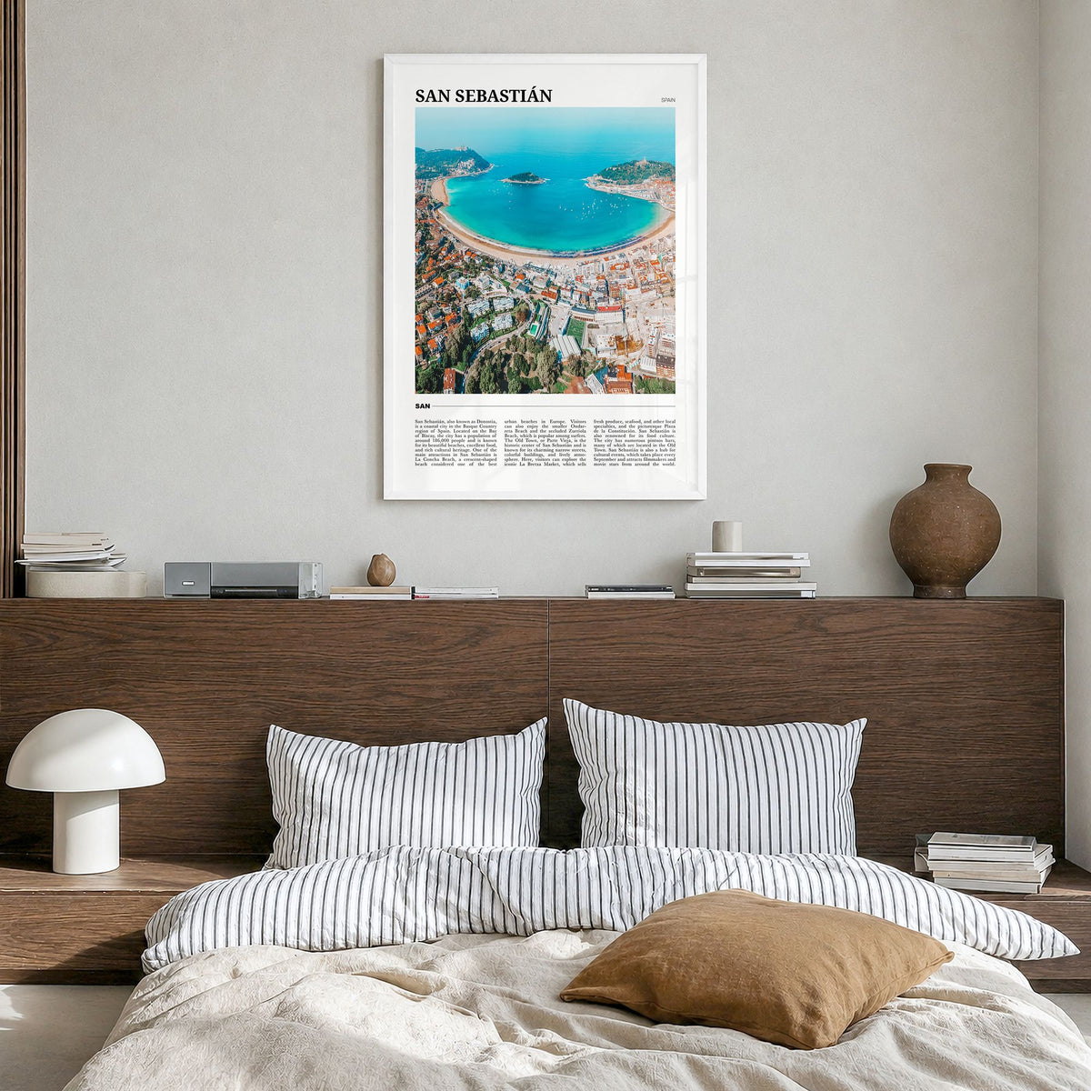 San Sebastián Travel Poster in a white wood frame, hanging in a bedroom