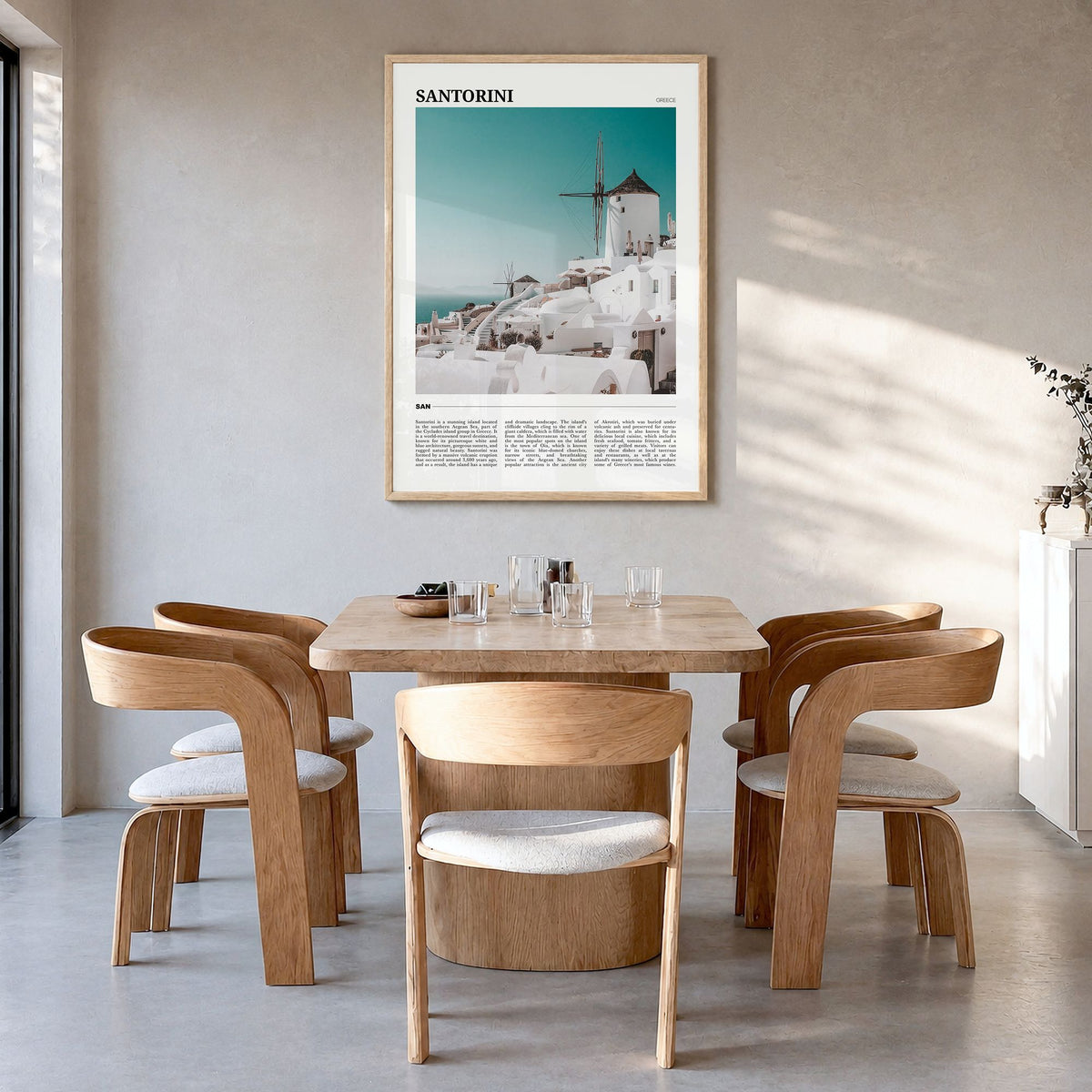 Santorini Travel Poster in a natural wood frame, hanging in a dining room