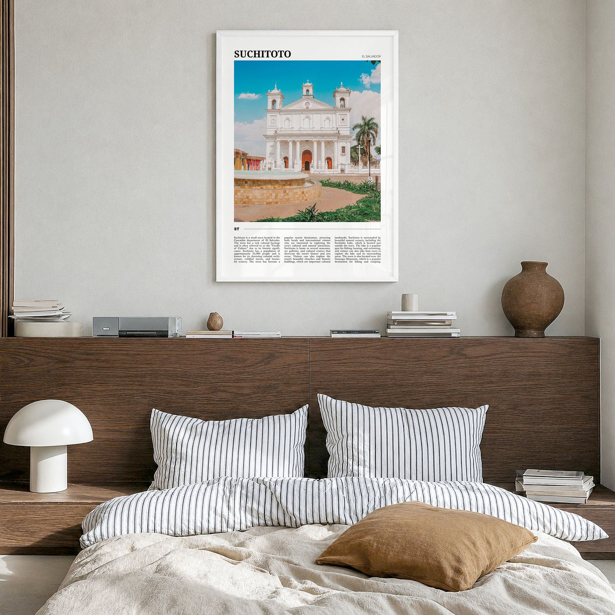 Suchitoto Travel Poster in a white wood frame, hanging in a bedroom