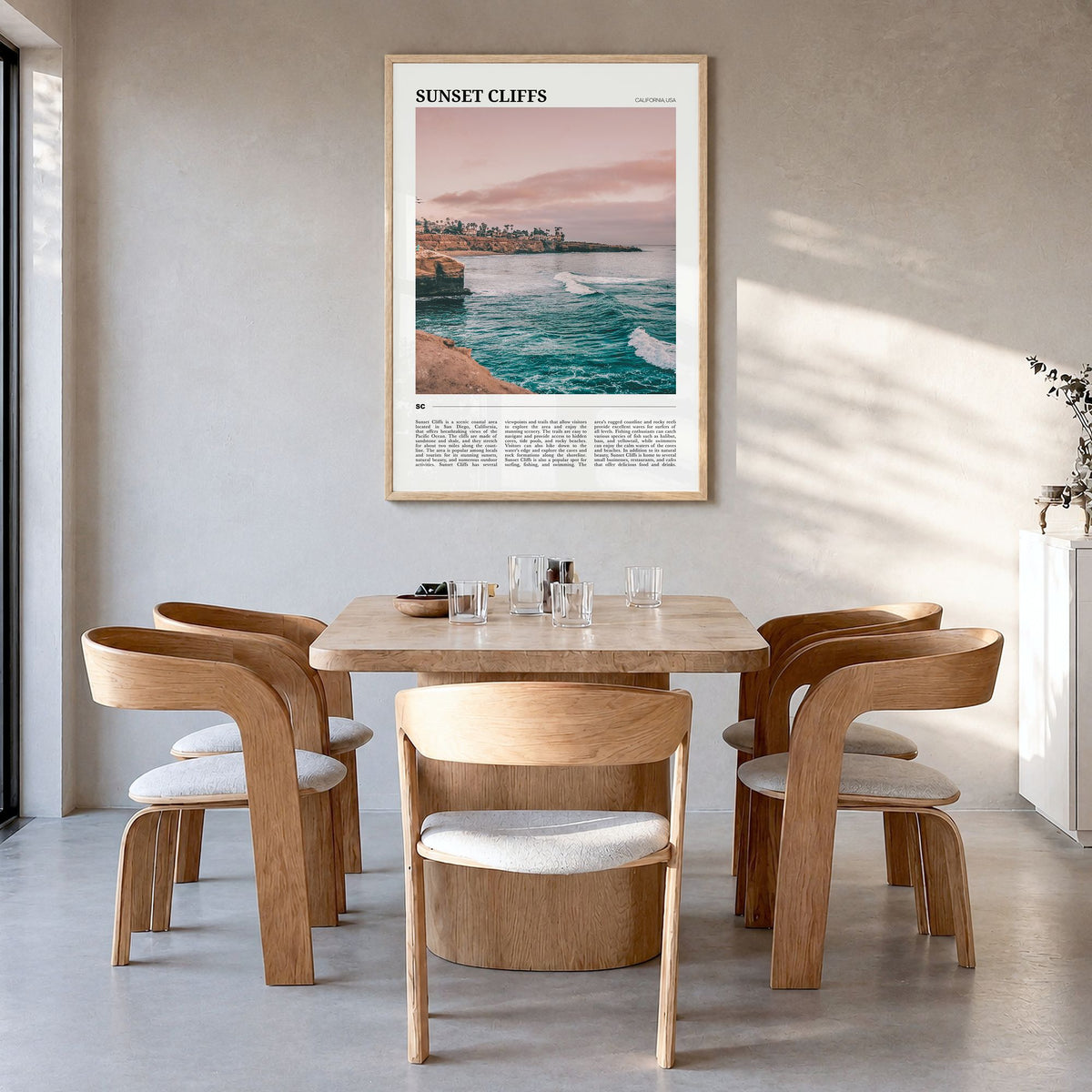 Sunset Cliffs Travel Poster in a natural wood frame, hanging in a dining room