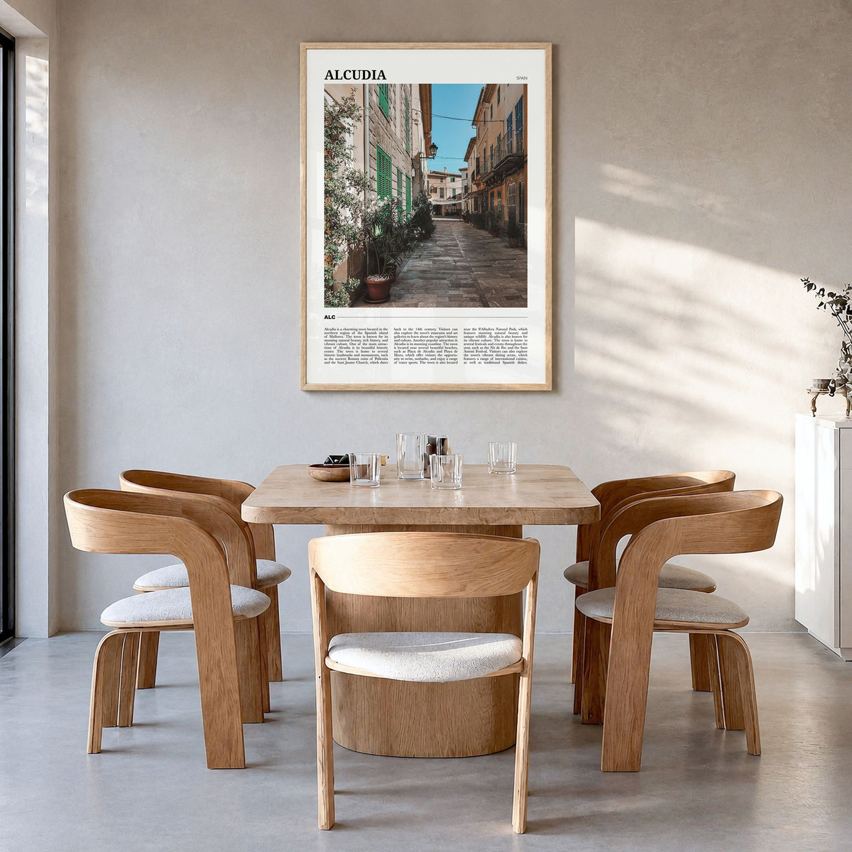 Alcudia Travel Poster in a natural wood frame, hanging in a dining room