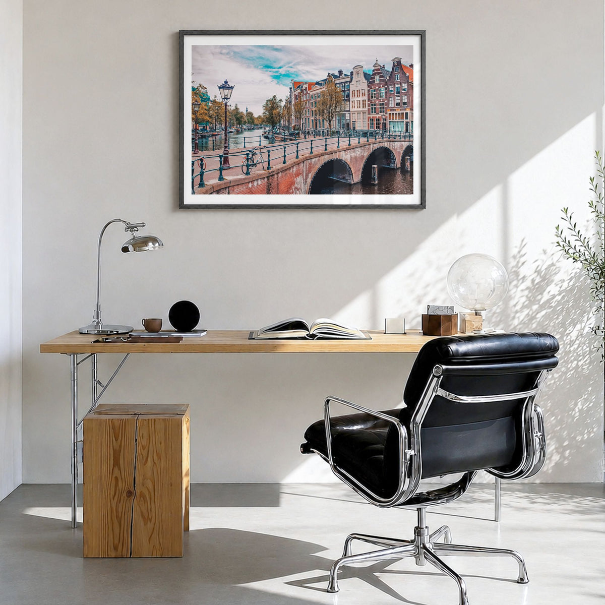 Amsterdam Photo Poster in a black wood frame, hanging in a bright home office, white border