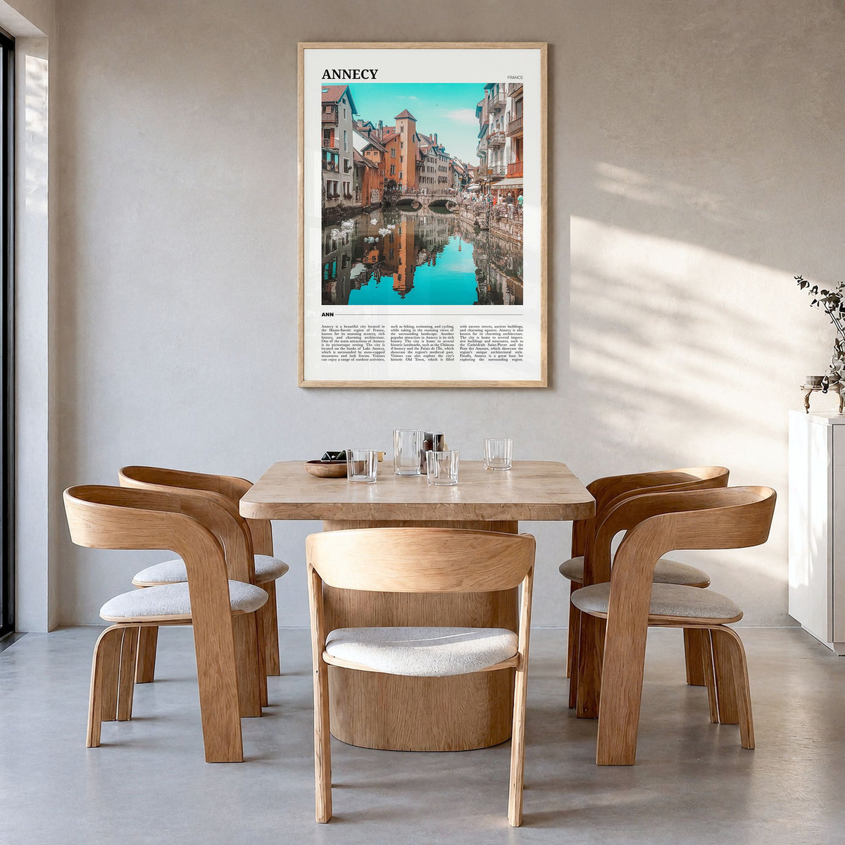 Annecy Travel Poster in a natural wood frame, hanging in a dining room
