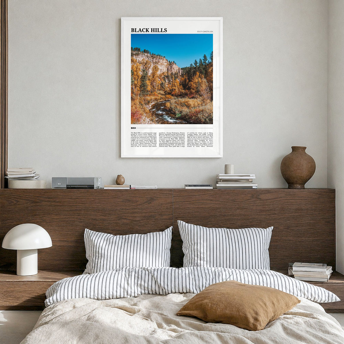Black Hills Travel Poster in a white wood frame, hanging in a bedroom