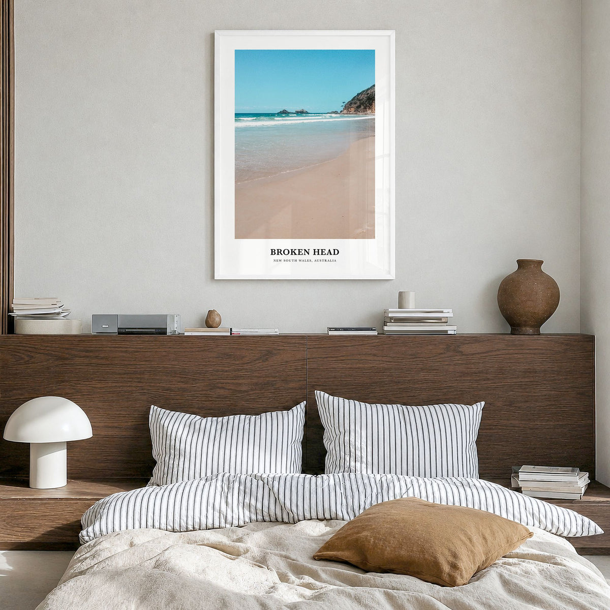 Broken Head Classic Poster in a white wood frame, hanging in a bedroom
