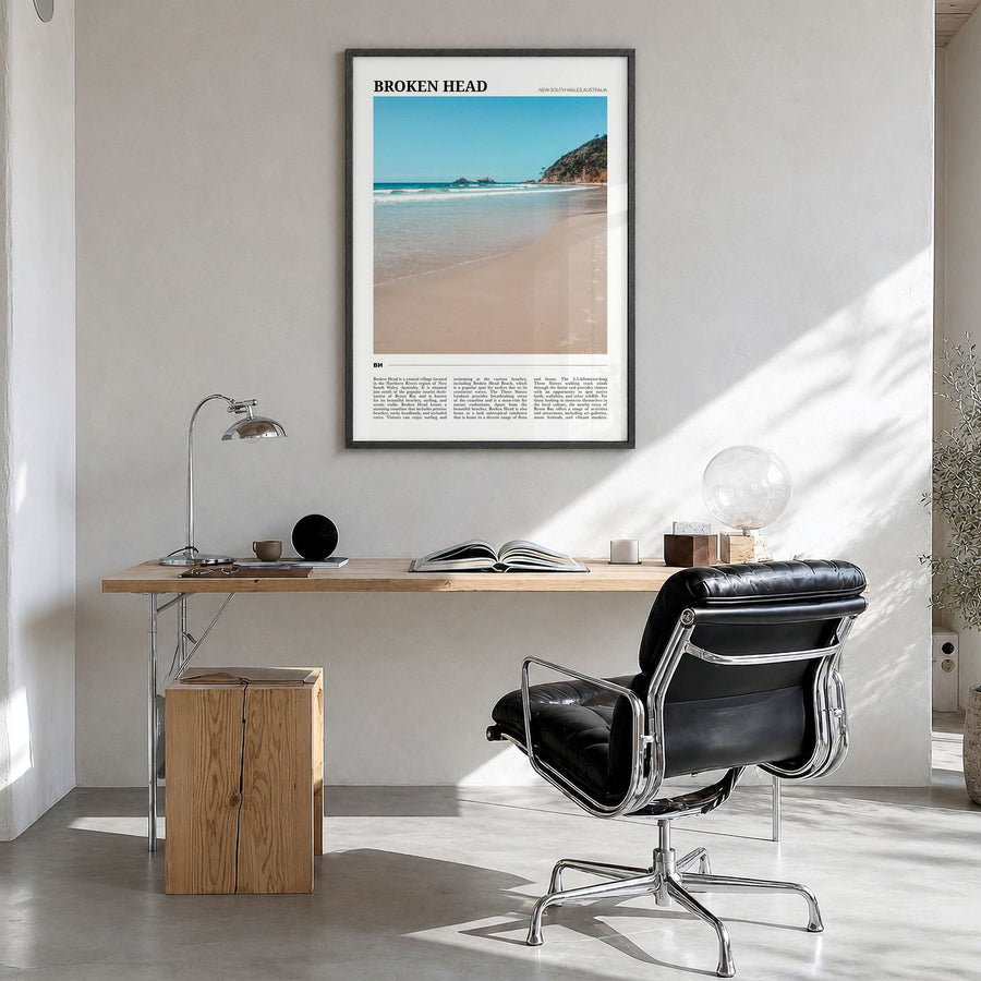 Broken Head Travel Poster in a black wood frame, hanging in a bright home office