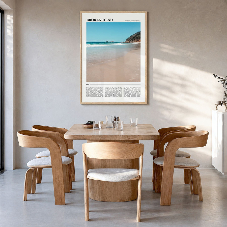Broken Head Travel Poster in a natural wood frame, hanging in a dining room