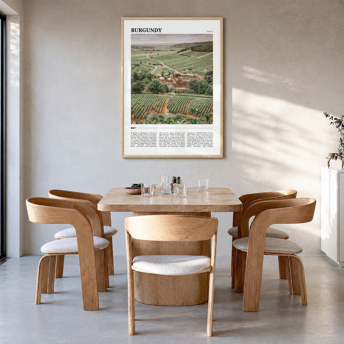 Burgundy Travel Poster in a natural wood frame, hanging in a dining room