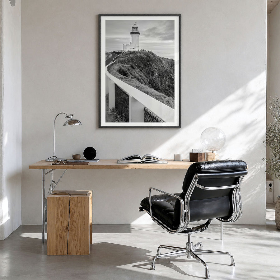 Byron Bay Photo Poster in a black wood frame, hanging in a bright home office, white border