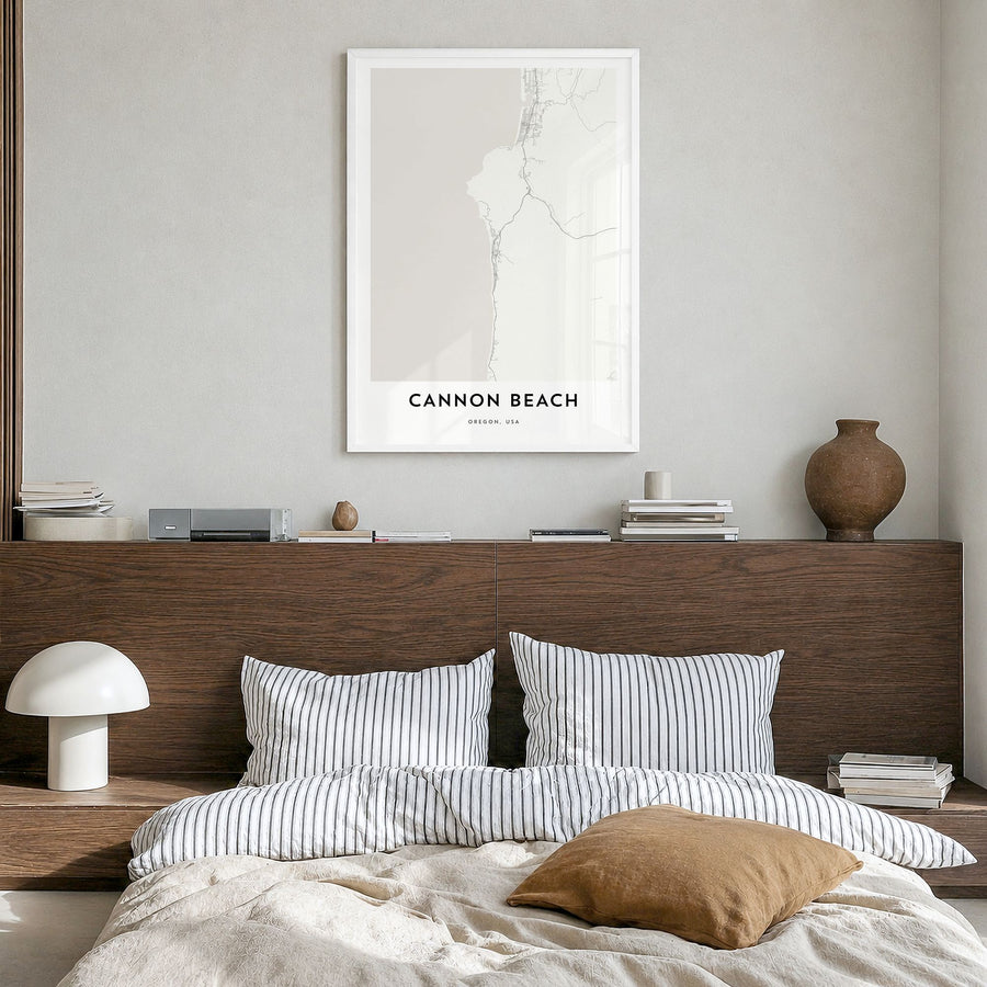 Cannon Beach Map Poster in a white wood frame, hanging in a bedroom