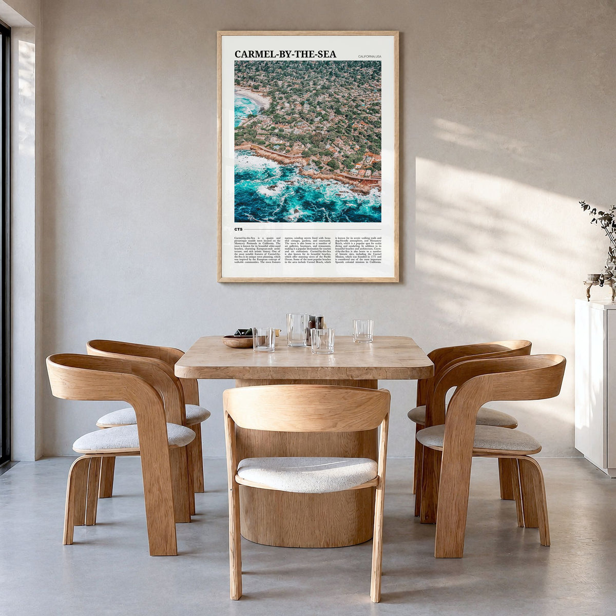 Carmel-by-the-Sea Travel Poster in a natural wood frame, hanging in a dining room