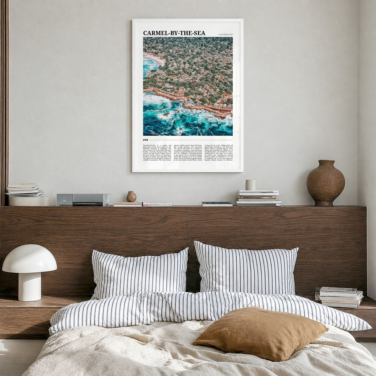 Carmel-by-the-Sea Travel Poster in a white wood frame, hanging in a bedroom