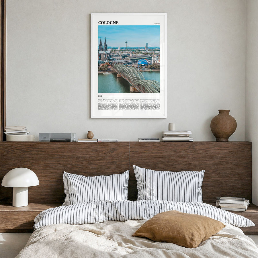 Cologne Travel Poster in a white wood frame, hanging in a bedroom
