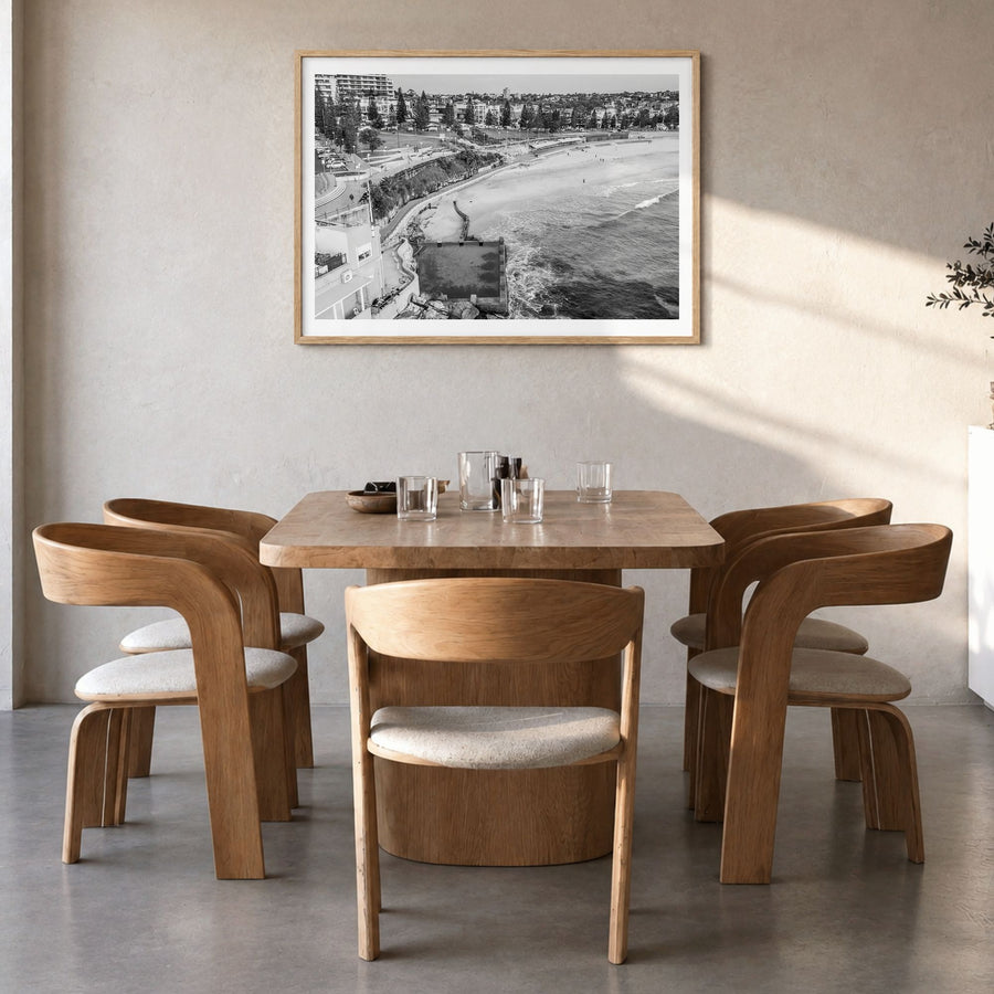 Coogee Beach Photo Poster in a natural wood frame, hanging in a dining room, white border