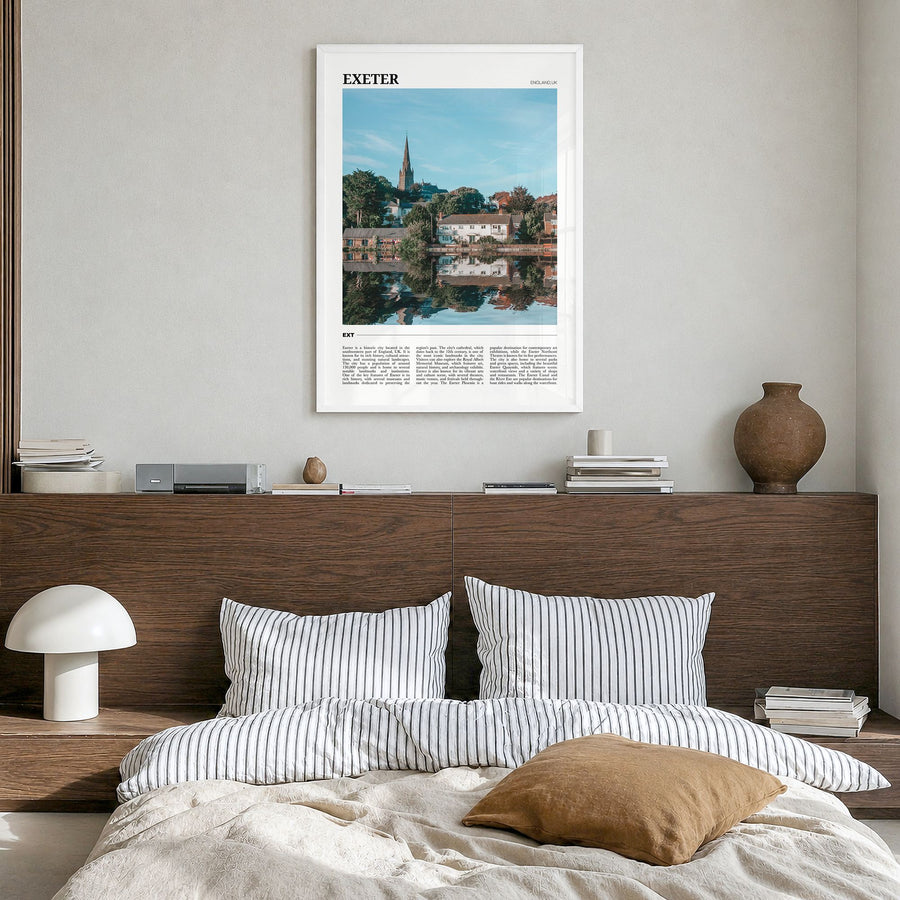 Exeter Travel Poster in a white wood frame, hanging in a bedroom