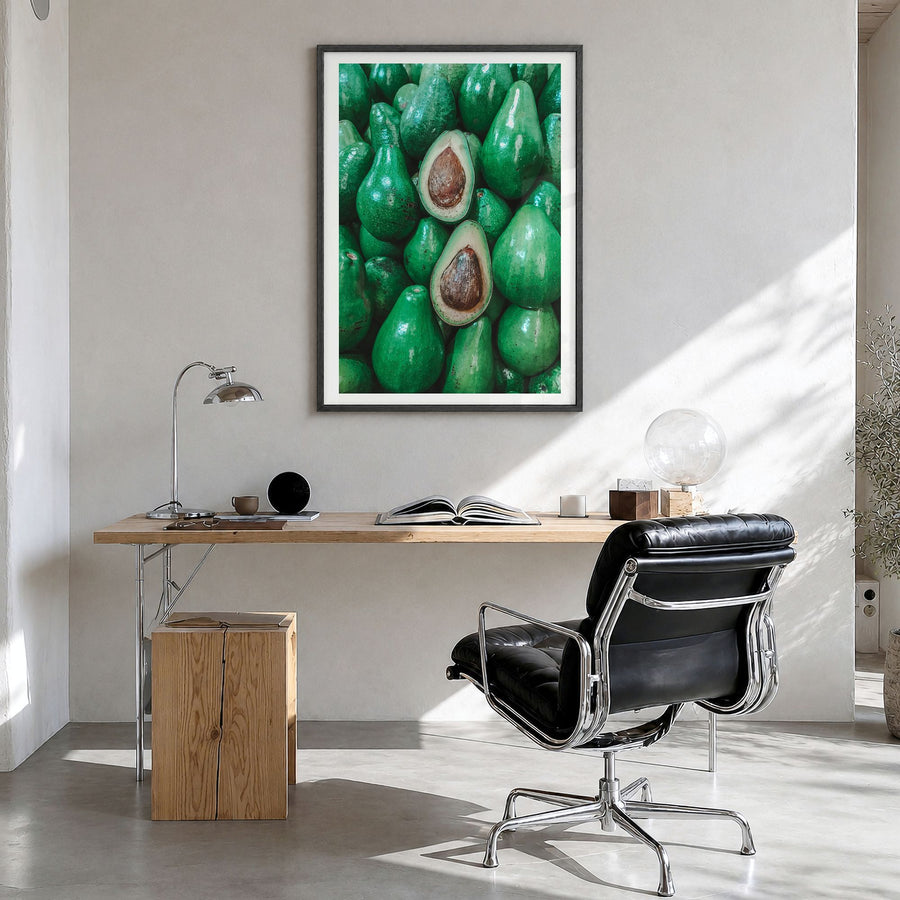 Green Avocados Photo Poster in a black wood frame, hanging in a bright home office, white border
