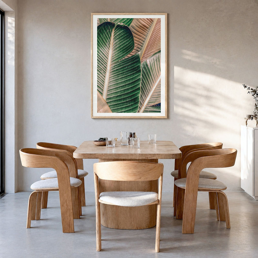 Green Palm Leaf Photo Poster in a natural wood frame, hanging in a dining room, white border