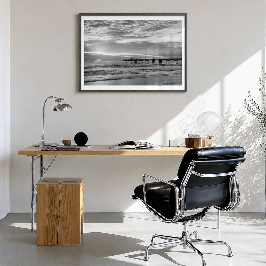 Jacksonville Beach Photo Poster in a black wood frame, hanging in a bright home office, white border