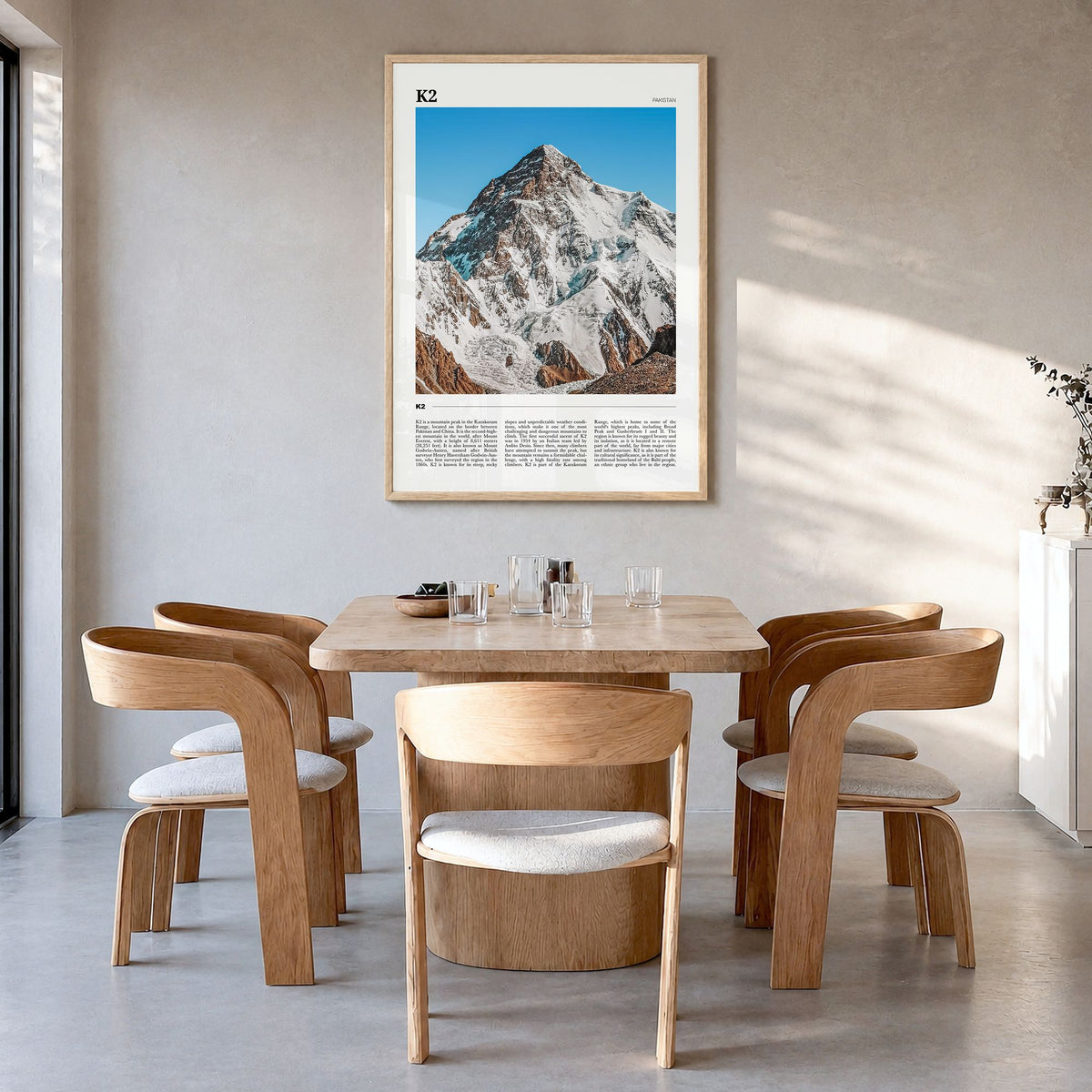 K2 Travel Poster in a natural wood frame, hanging in a dining room