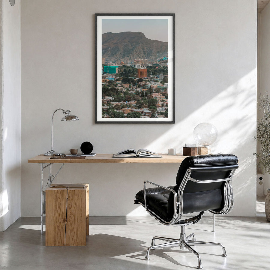 Kabul Photo Poster in a black wood frame, hanging in a bright home office, white border