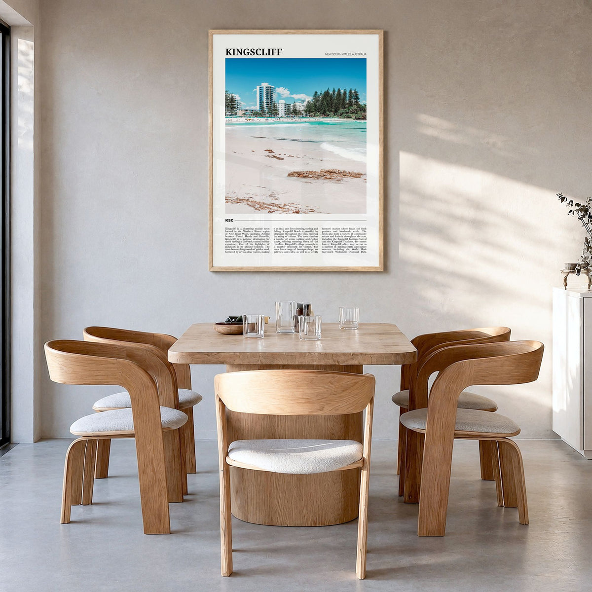 Kingscliff Travel Poster in a natural wood frame, hanging in a dining room