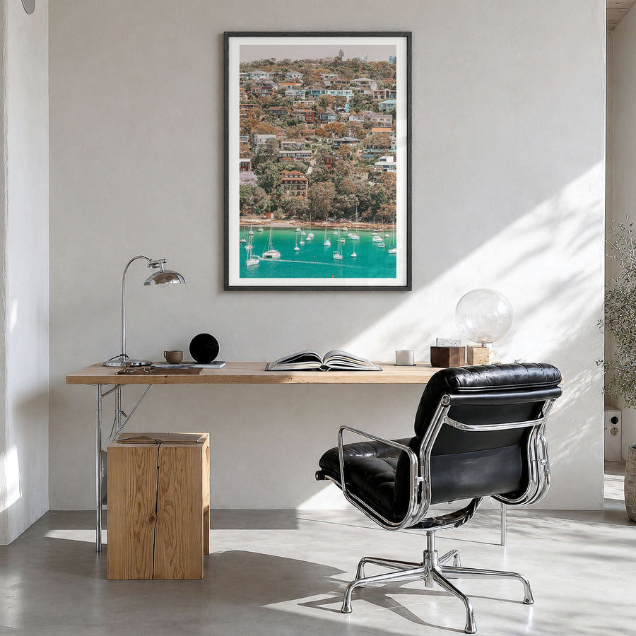 Manly Beach Photo Poster in a black wood frame, hanging in a bright home office, white border