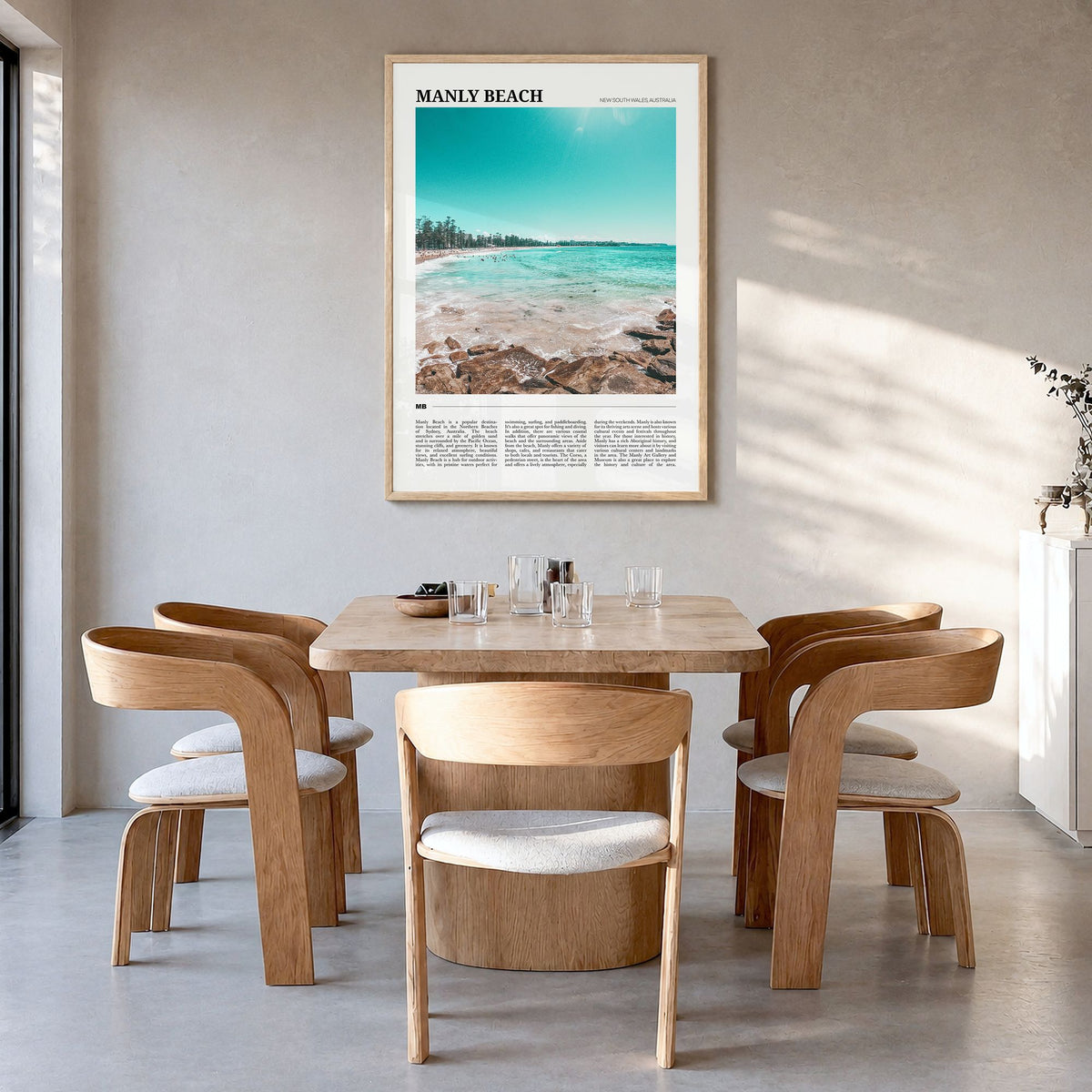 Manly Beach Travel Poster in a natural wood frame, hanging in a dining room