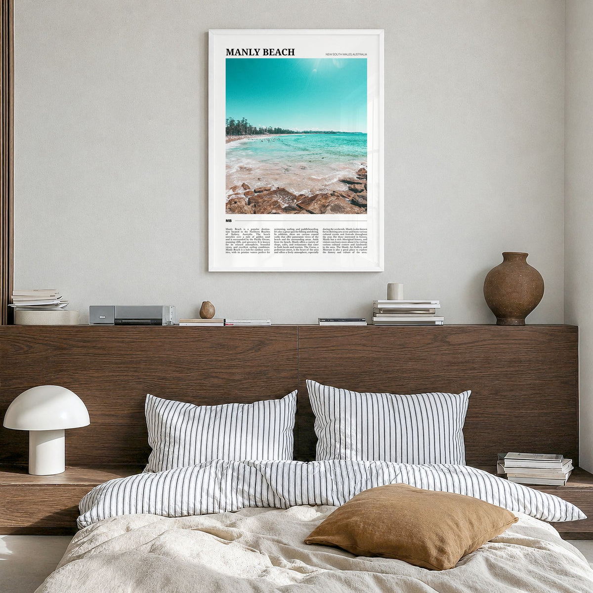 Manly Beach Travel Poster in a white wood frame, hanging in a bedroom
