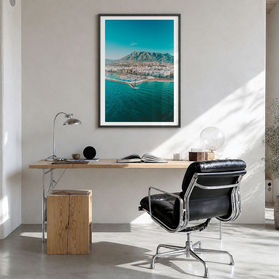 Marbella Photo Poster in a black wood frame, hanging in a bright home office, white border