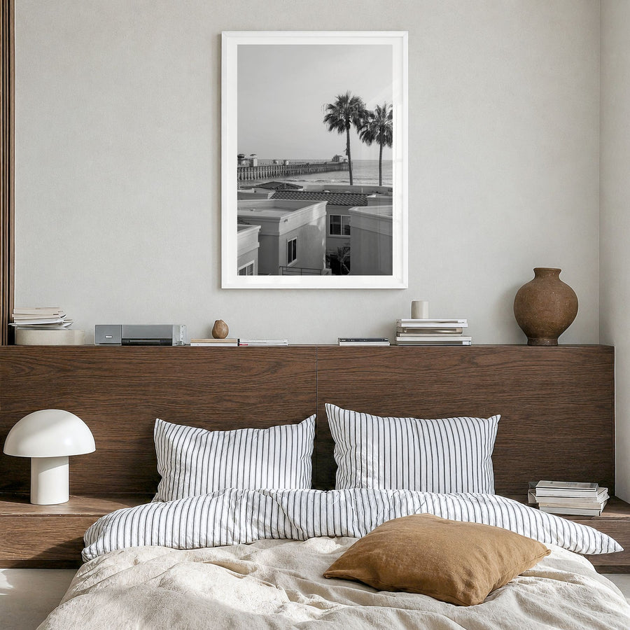 Oceanside Photo No 1 Poster in a white wood frame, hanging in a bedroom, white border