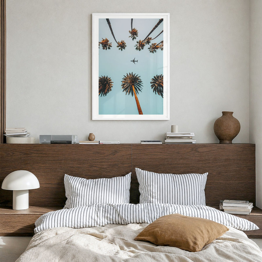 Palm Trees, Sky and Aircraft Photo Poster in a white wood frame, hanging in a bedroom, white border