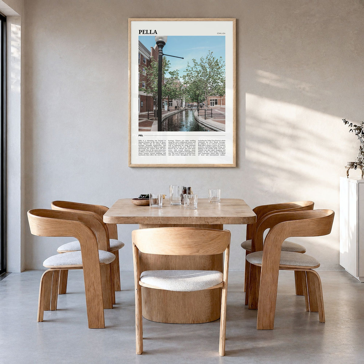 Pella, Iowa Travel Poster in a natural wood frame, hanging in a dining room