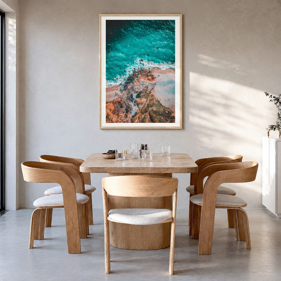 Point Dume Photo Poster in a natural wood frame, hanging in a dining room, white border
