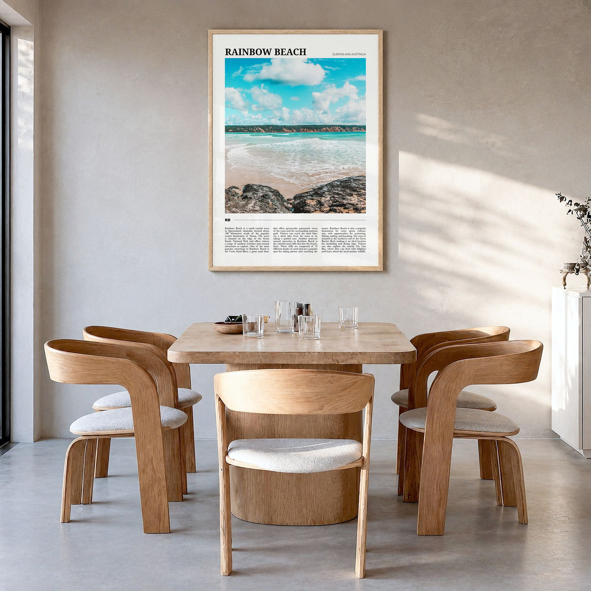 Rainbow Beach Travel Poster in a natural wood frame, hanging in a dining room