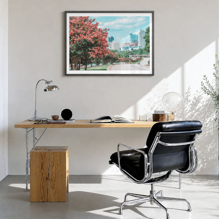 Raleigh Photo Poster in a black wood frame, hanging in a bright home office, white border